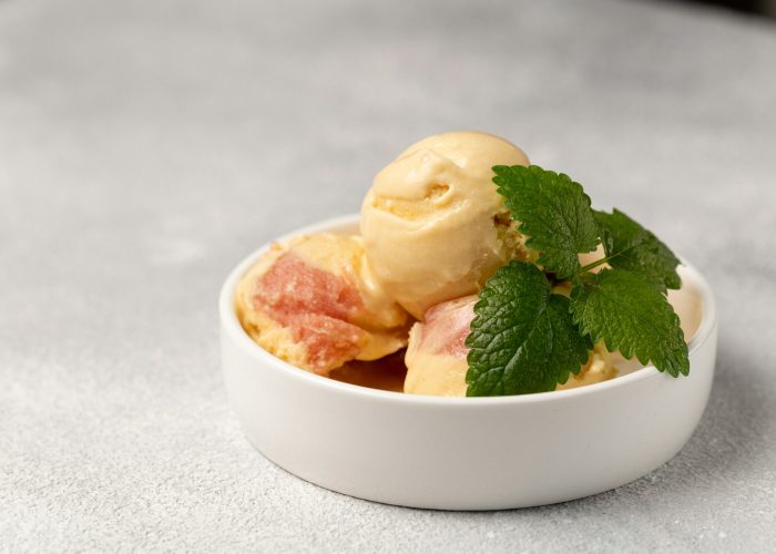 Peach ice cream with strawberry sorbet, decorated with a sprig of mint